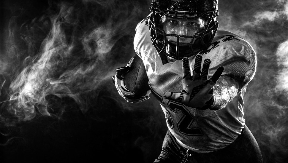 Football player on stadium with smoke and lights.