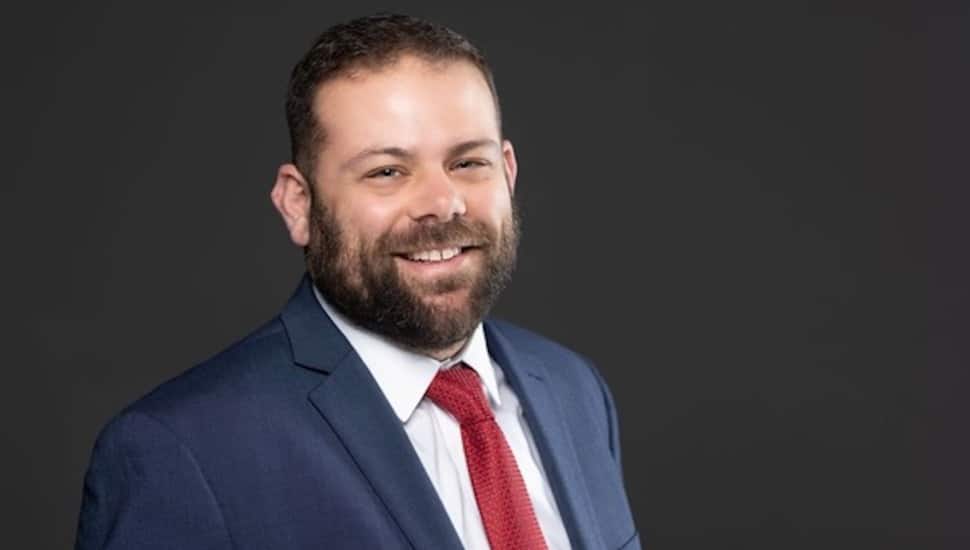 Headshot of attorney in blue suit and red tie.