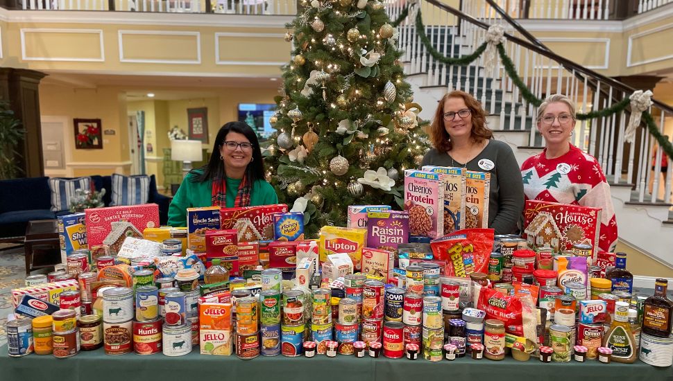 Freedom Village at Brandywine staff members stand behind a large collection of food and canned goods.