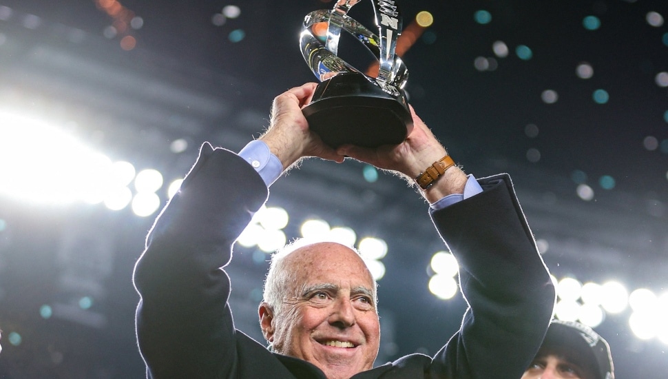 Jeffrey Lurie holds trophy in the air.