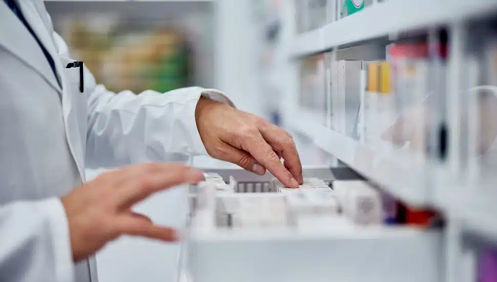 Male pharmacist choosing a medicine from the drawer.