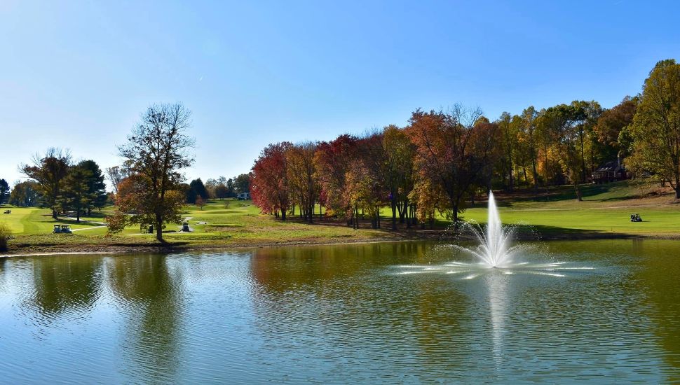 Green grass, trees, and lake at Penn Oaks Golf Club.