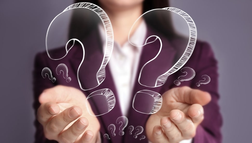 Businesswoman holds question marks in her hands.