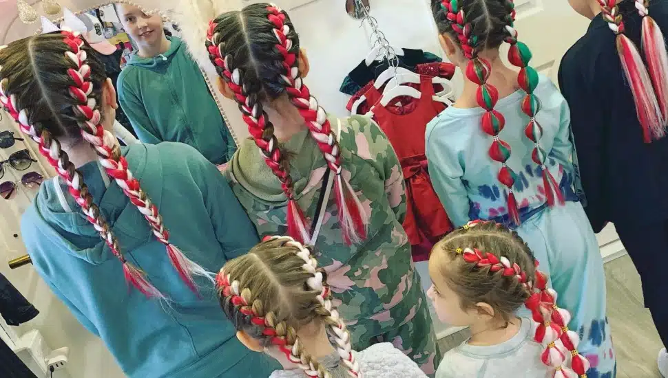 Six young girls with colorful braids in their hair.