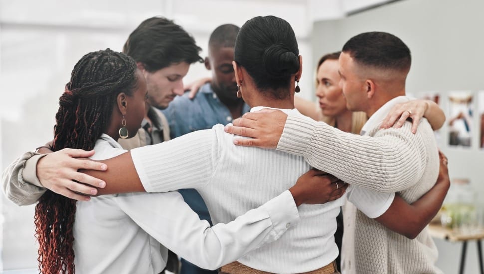 People hug each other in a circle for support.