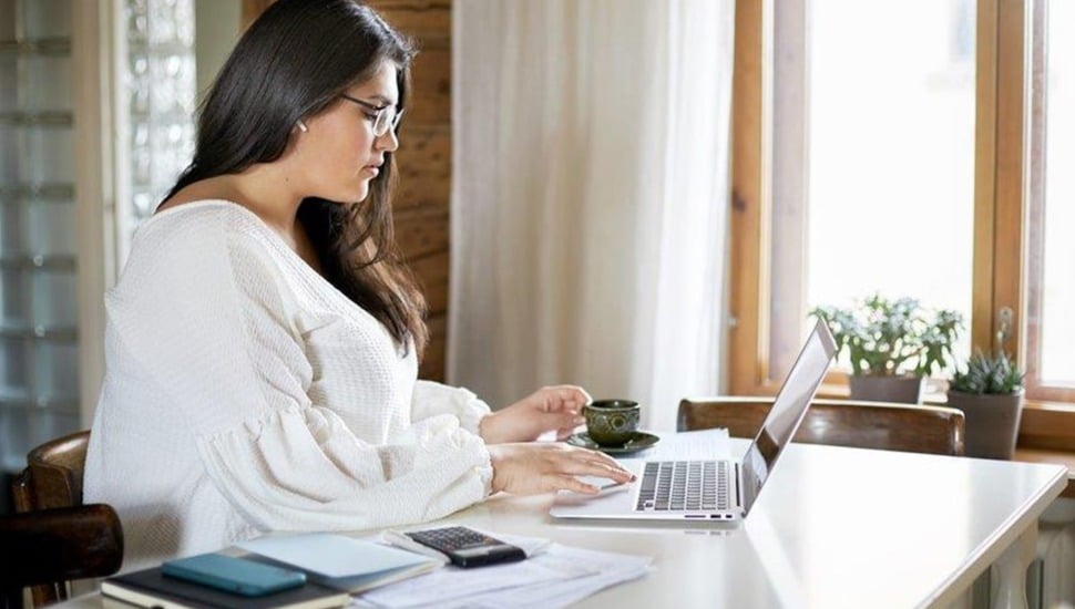 Woman does her taxes at a kitchen table.