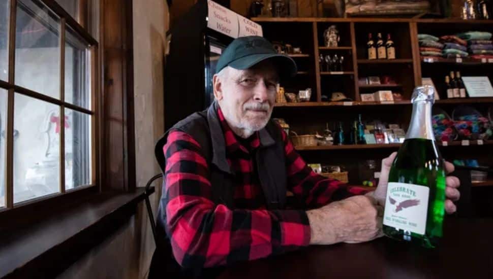 Jerry Forest holds bottle of green wine.