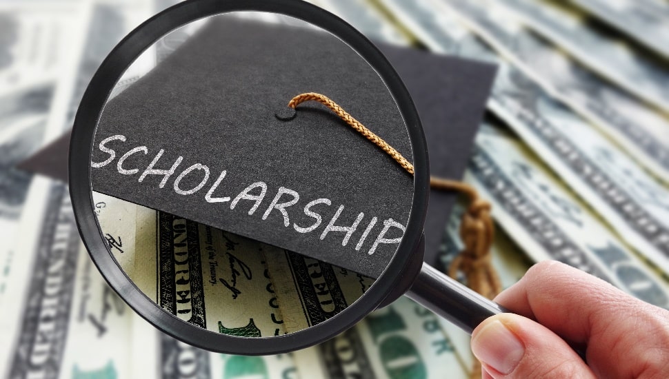 Scholarship graduation cap on money with magnifying glass