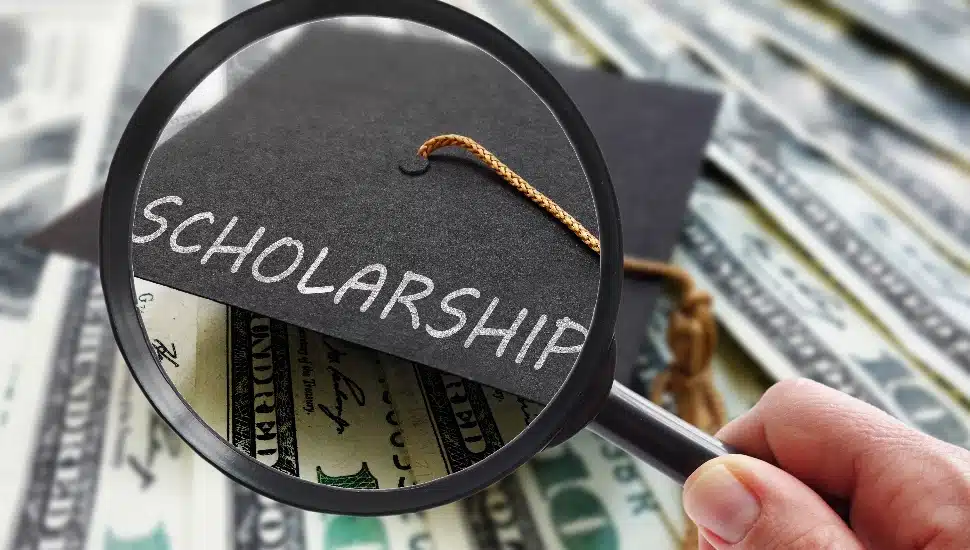 Scholarship graduation cap on money with magnifying glass