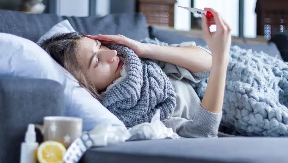 Sick girl lying in bed wrapped in blanket.
