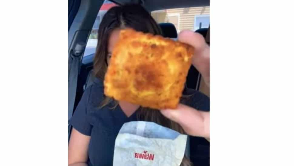 A YouTube reviewer holds up a Wawa toasted ravioli while doing a review in her car.