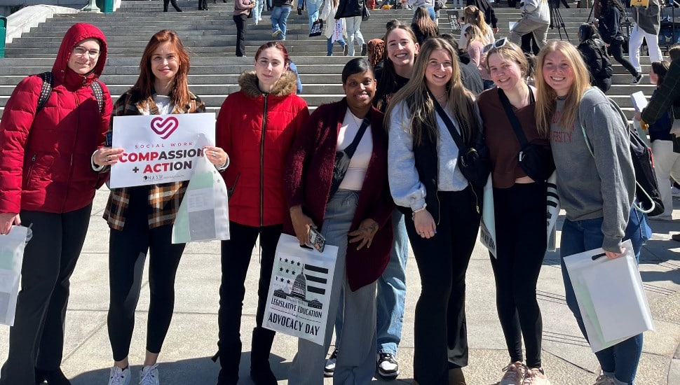 College students stand on the steps of a state capitol.