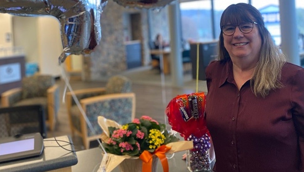 Woman celebrates 45 years working at bank with flowers and balloons.