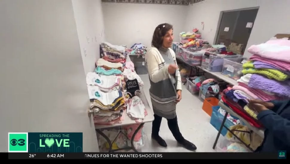 Laurieann Tebben surrounded by baby clothes and other gifts for babies.