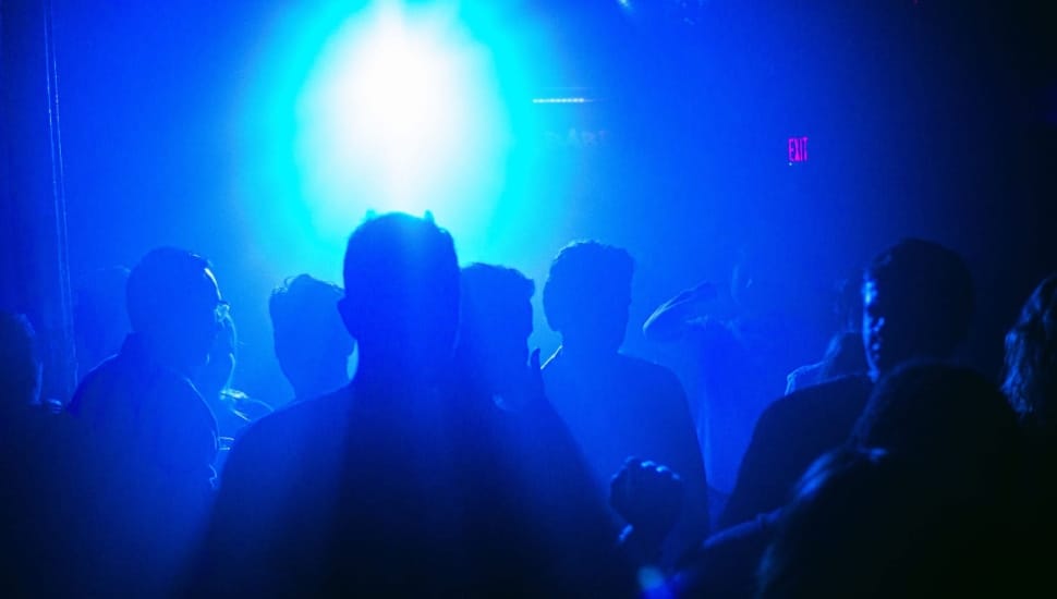 People enjoying themselves inside The Barbary, with blue lights illuminating the club.
