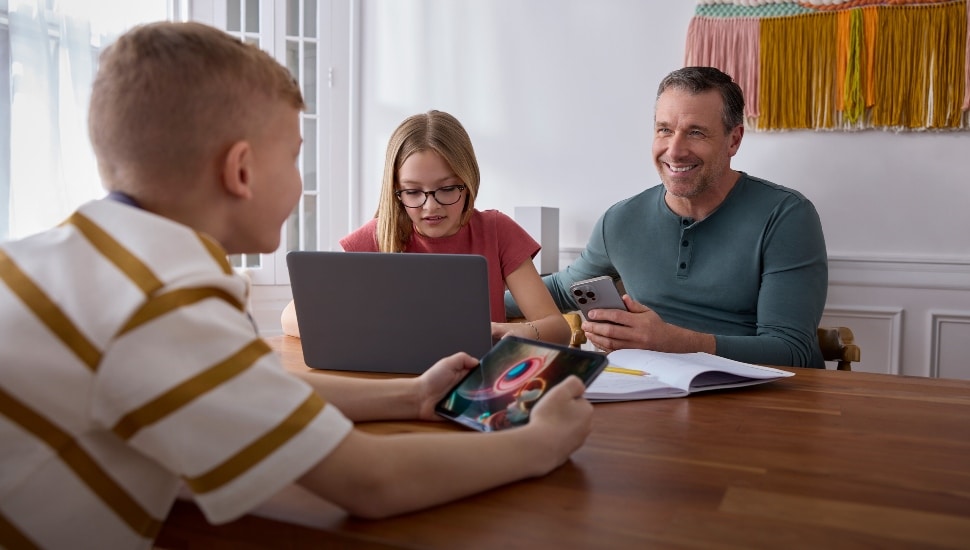 A man with two pre-adolescents enjoying electronic devices with internet.