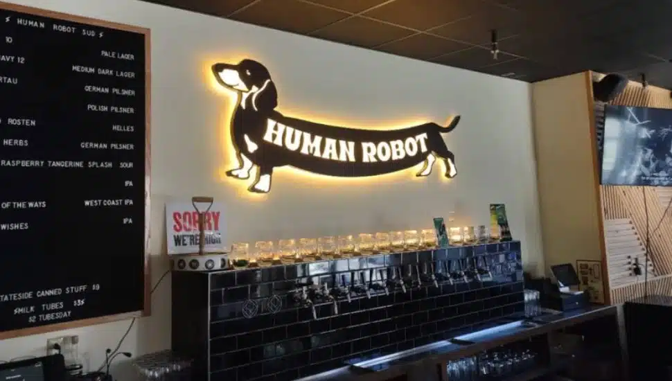 Human Robot Brewing's neon sign displayed over beer taps on their back bar.