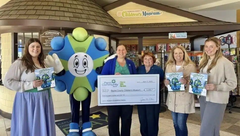Members of Penn Community Bank stand with the mascot, Sprout, and copies of the book, "Sprout $aves the Day." The man in the middle also holds a large check made to the order of Bucks County Children's Museum.