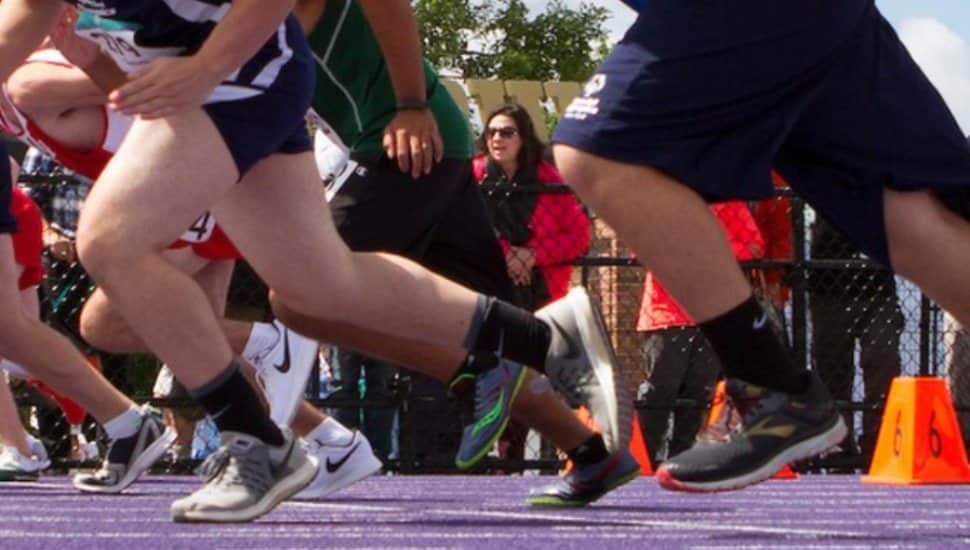 Runners burst off the track in a sprint.