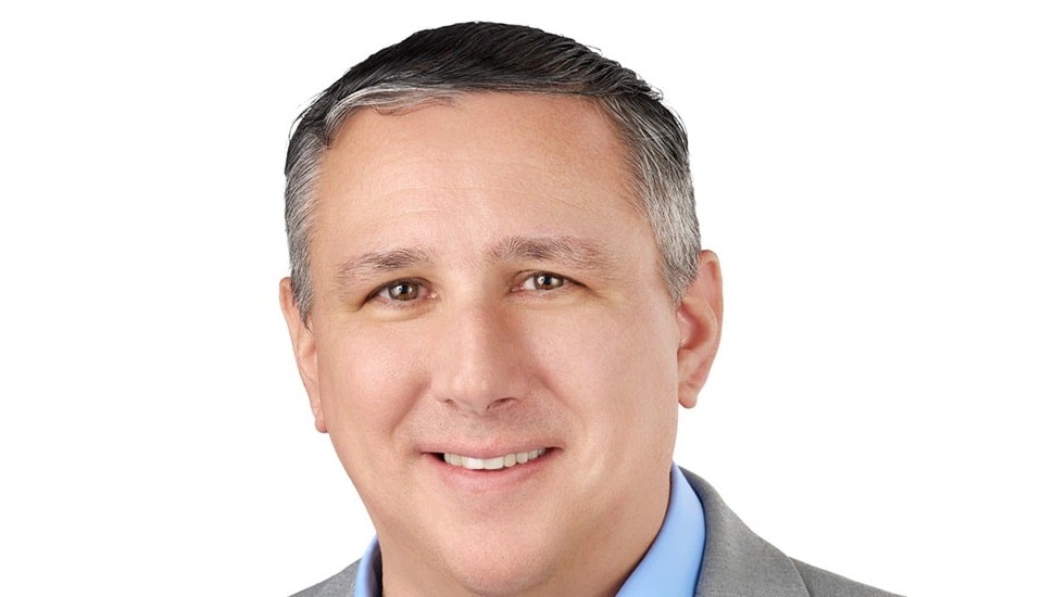 Headshot of middle-aged white male bank executive with gray suit and blue collared shirt.