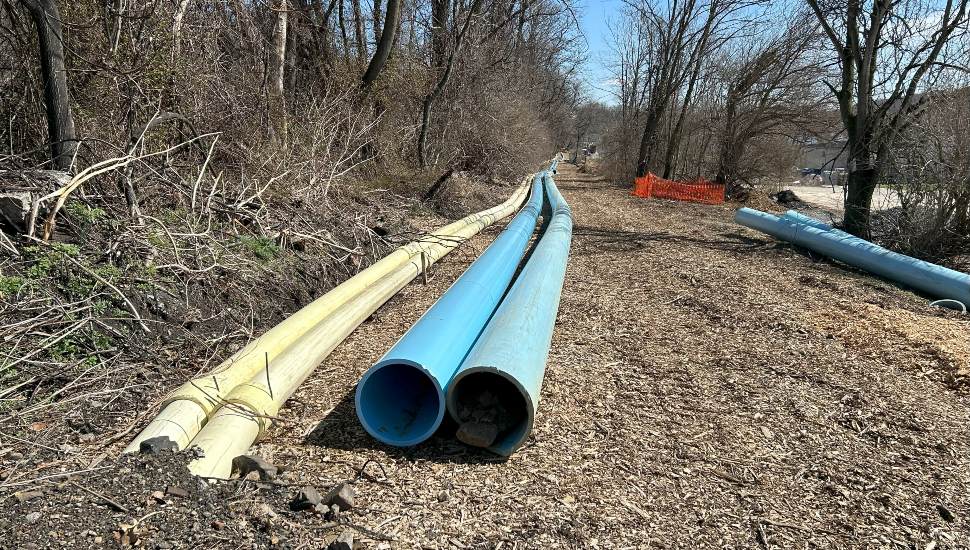 A close up view of a new pipe to be used by Pennsylvania American Water for water main slip lining in Coatesville. It's in a cleared area on fresh dirt surrounded by trees.