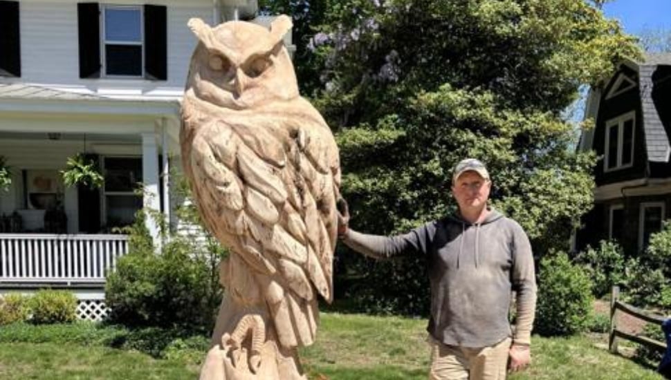 Viacheslav Kuzema stands by his Yardley tree trunk sculpture