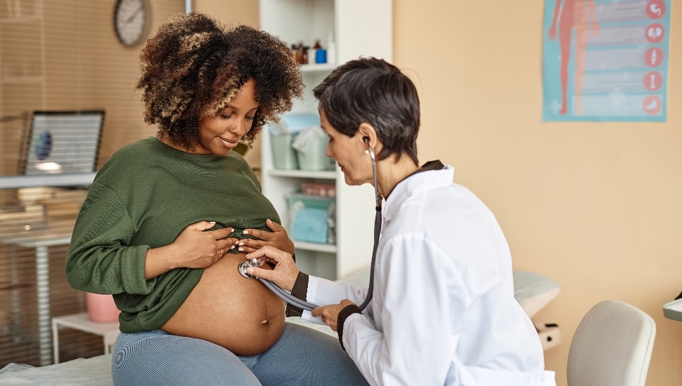expectant mother sitting on medical table in clinic