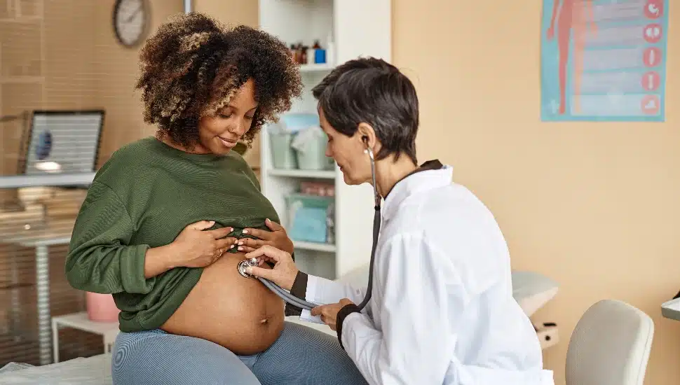 expectant mother sitting on medical table in clinic