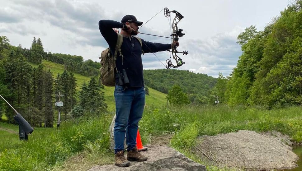 A man firing a bow and arrow in a field.