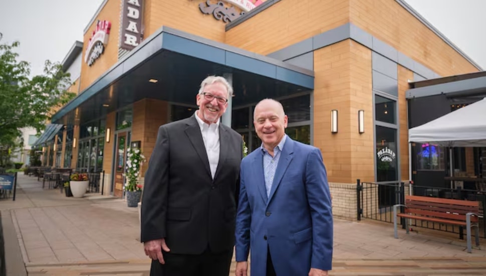 Larry Cohen and Barry Gutin in front of building.