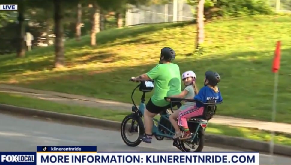 Father and his children riding a bike outside.