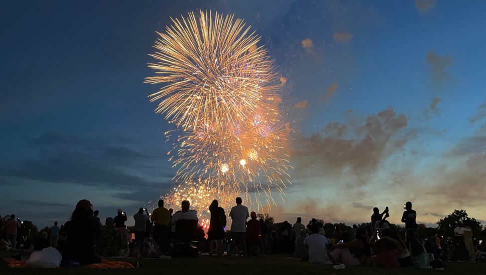 Large crowd of people watching Fourth of July celebrations late at night.