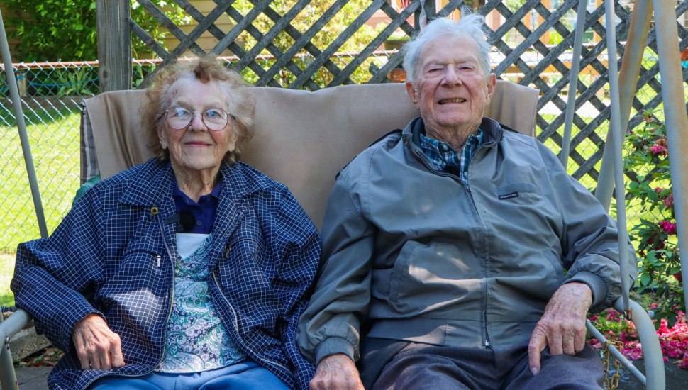 Jim and Margaret St. Clair sitting beside each other on a chair swing.