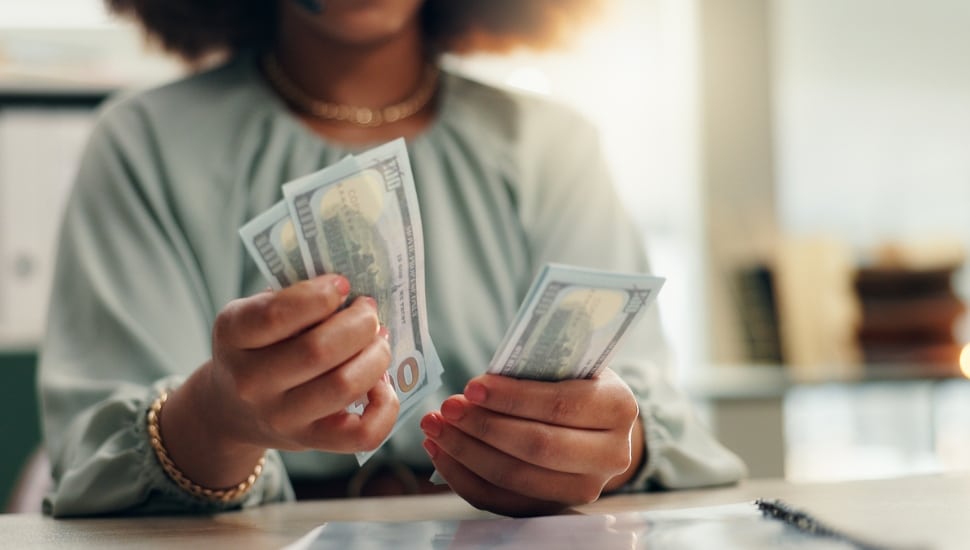 Woman counting hundred dollar bills.