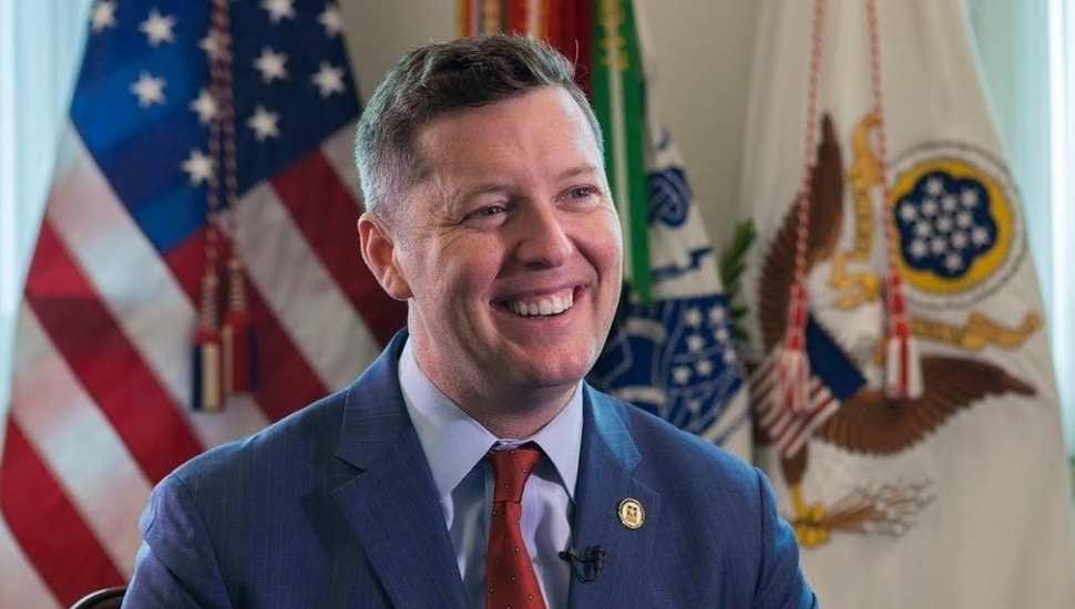 Patrick Murphy smiling in front of American flag.
