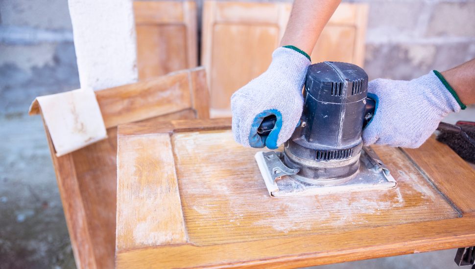 Someone sanding wood panel.