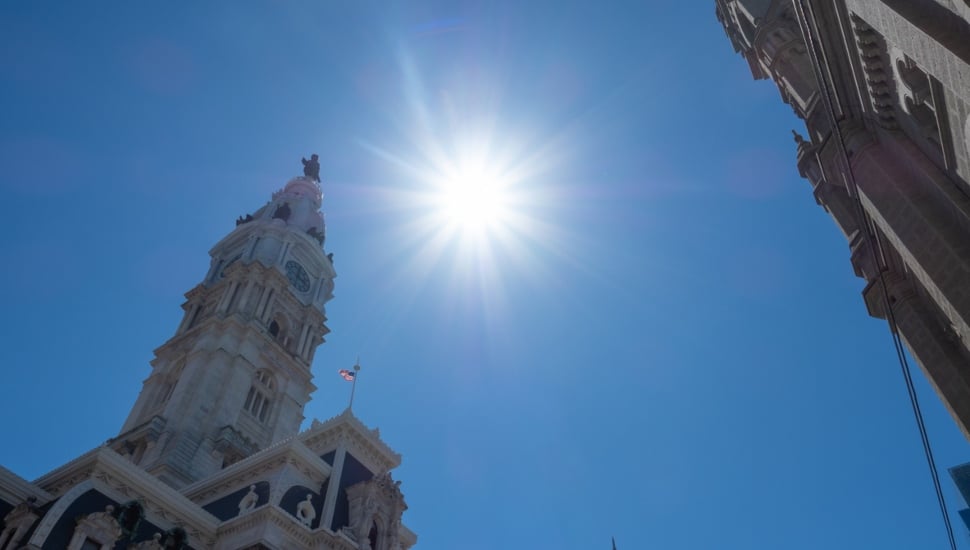 Sun in the sky with building in frame.