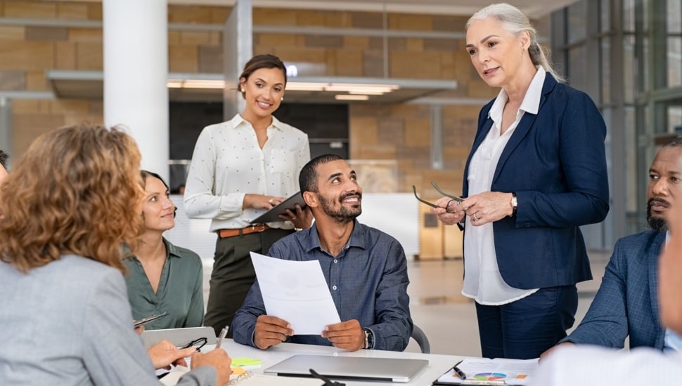 Middle-aged female business leader talks with colleagues.