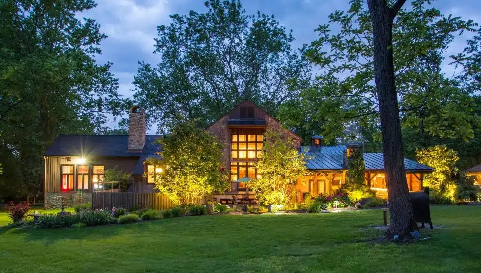 Exterior of converted stone bank barn at night.