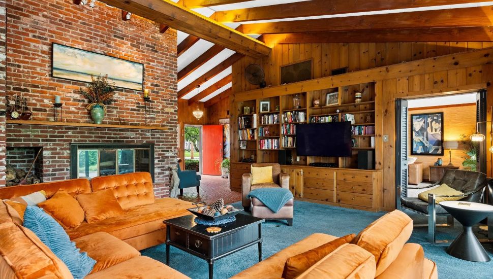 Living room of Quakertown home with a large couch, bookshelves and wood paneling.