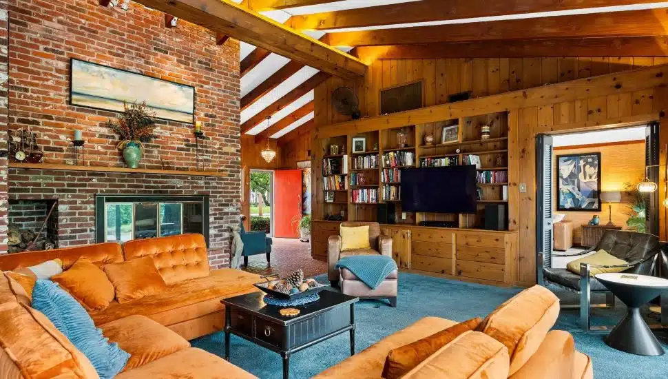 Living room of Quakertown home with a large couch, bookshelves and wood paneling.