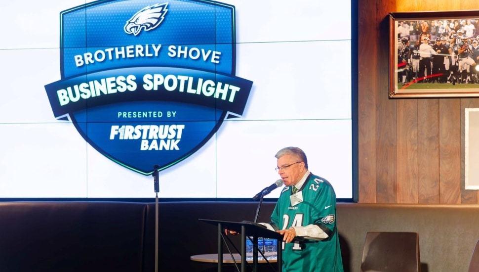 Older man in a football jersey speaks at a podium.