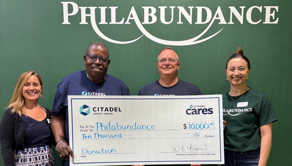 Two male bank executives present giant check to nonprofit officials.