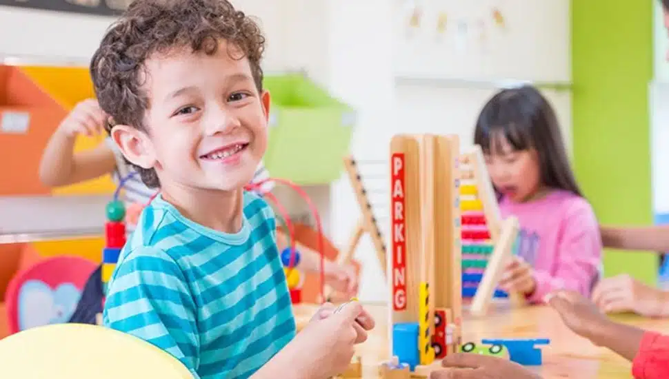 Child smiling at camera while playing with toys.
