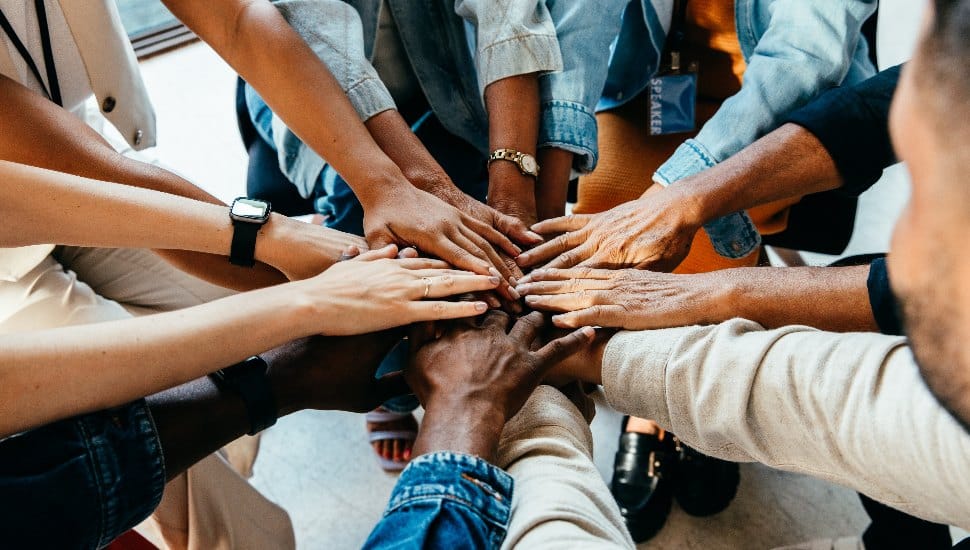 A diverse group of people join hands in a circle, symbolizing unity, teamwork, and community collaboration.