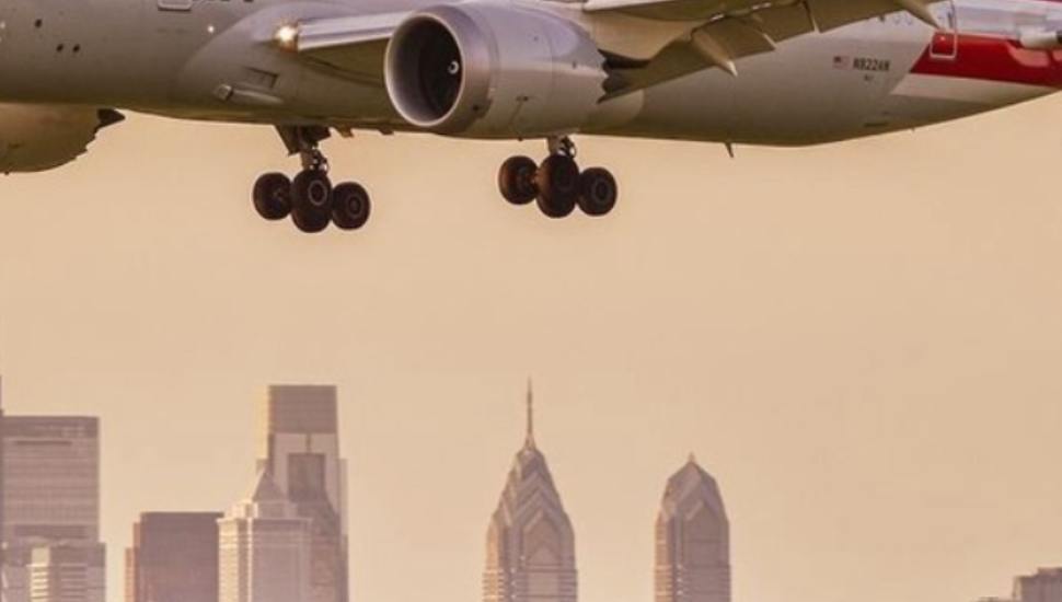 Plane flying with Philadelphia skyline in the background.