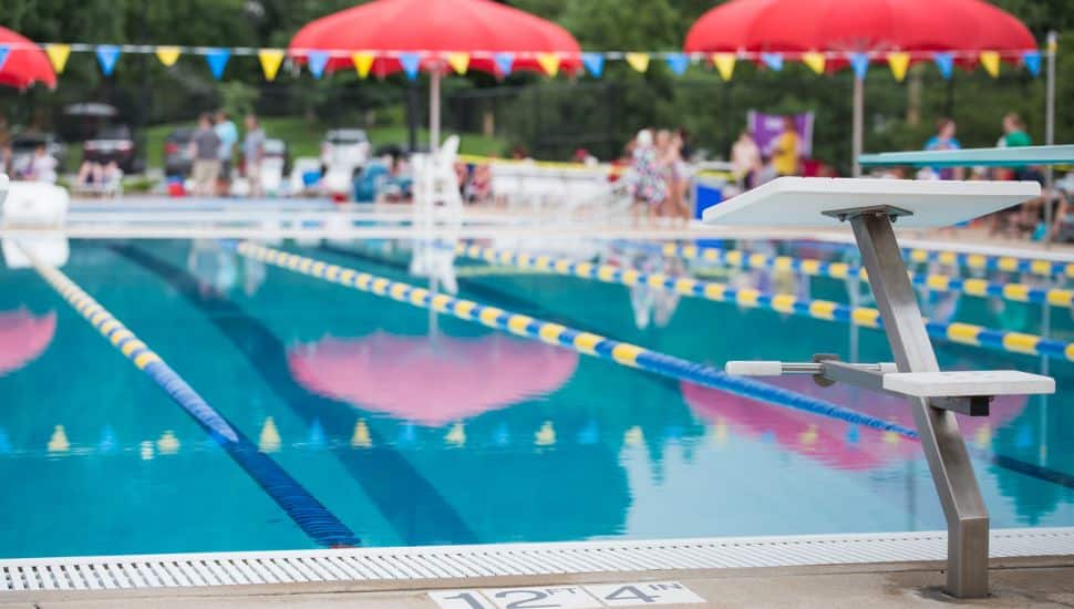 A diving block stands before the empty race lanes in a swimming pool.