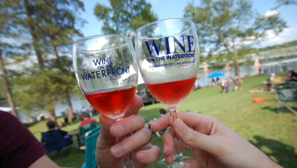 People holding wine glasses with wine samples labeled Wine on the Waterfront.
