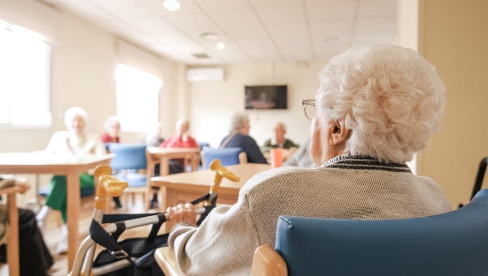 Elderly woman sitting in chair in nursing home.