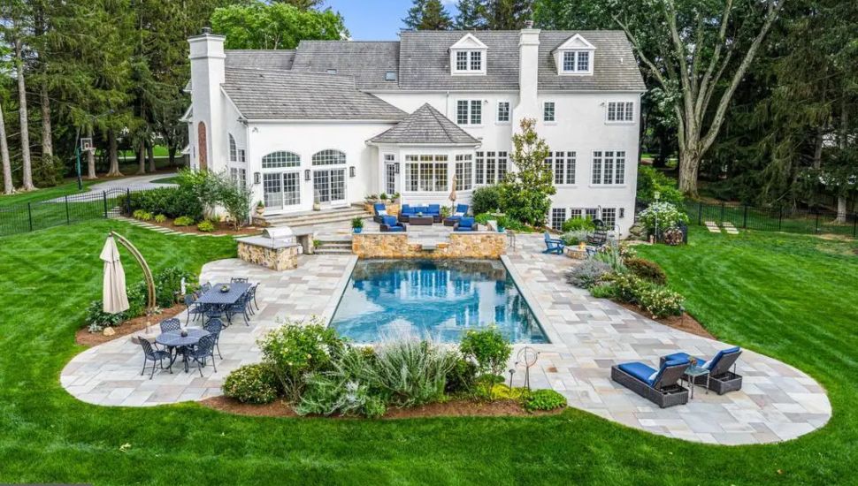 Rear of mansion with pool and lounge chairs.